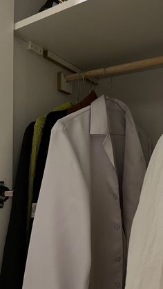 a white coat hanging on a rack in a closet