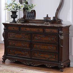 an ornate dresser with mirror and vase on top