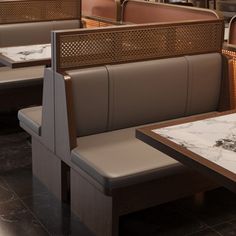 the inside of a restaurant with marble tables and booths on either side of the table