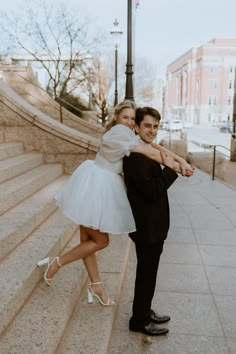 a man in a tuxedo is hugging a woman on the steps