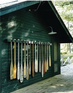 there are many paddles hanging on the side of this building and it is green