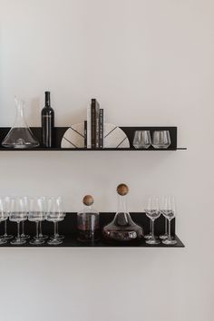 two black shelves filled with wine glasses and bottles