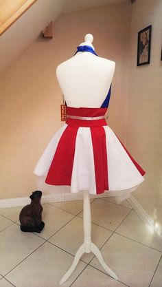 a mannequin dressed in a red, white and blue dress next to a cat