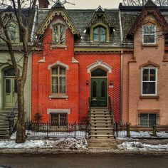 a red brick house with green door and steps leading up to the front entrance in winter