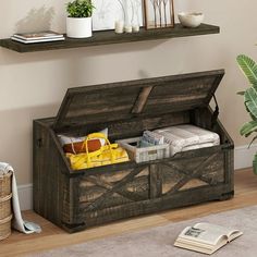 an open trunk sitting on top of a wooden floor next to a potted plant