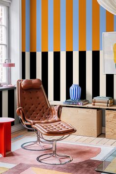 a living room with striped wallpaper and leather chair in the middle, colorful rug on the floor