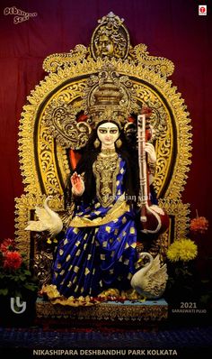 the statue is sitting on top of a golden throne with birds around it and flowers in front of it