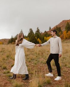 a man and woman holding hands in an open field