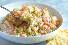 a white bowl filled with shrimp salad next to crackers