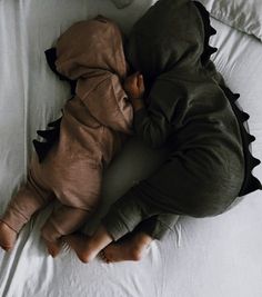 a baby laying on top of a bed next to a pillow and blanket with a stuffed animal in it's arms