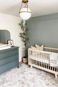 a baby's room with a crib, dresser and mirror on the wall