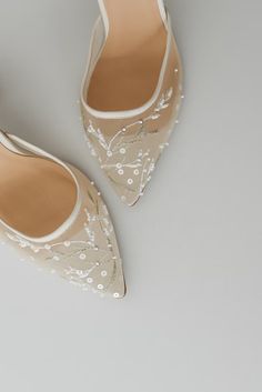 a pair of white shoes with pearls on the toes and heels are sitting next to each other