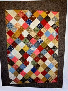 a multicolored patchwork quilt hanging on the wall