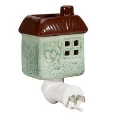 a green and brown ceramic house shaped outlet with a plug in the wall next to it