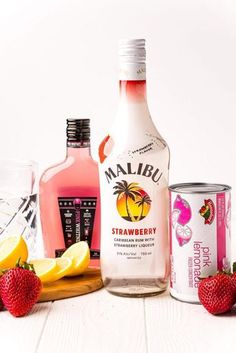 several different types of alcohol are arranged on a table next to lemons and strawberries