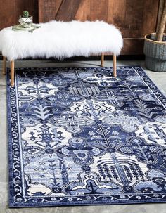 a blue and white rug with a bench in front of it