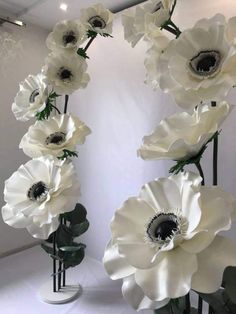 there are many white flowers in the vases on this table top, and one is tall