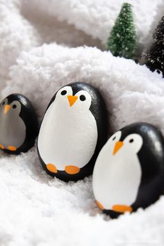 three penguins painted on rocks in the snow