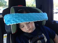 a young boy sleeping in the back seat of a car with a blue pillow on his head