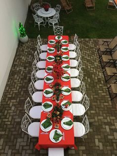 a long table set up with white plates and red napkins for an outdoor dinner