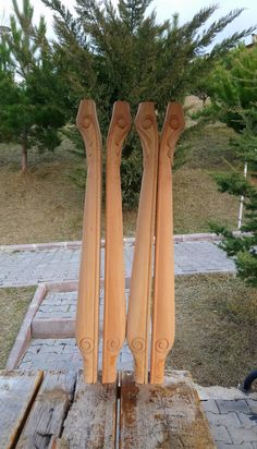 two wooden carvings sitting on top of a piece of wood in front of a tree