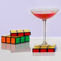 a glass filled with pink liquid next to two rubik cubes