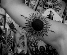 a black and white photo of a sun tattoo on the arm