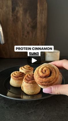 a person is holding a cinnamon buns on a plate with the words protein cinnamon buns