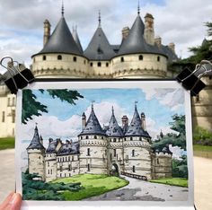 a hand holding up a drawing of a castle