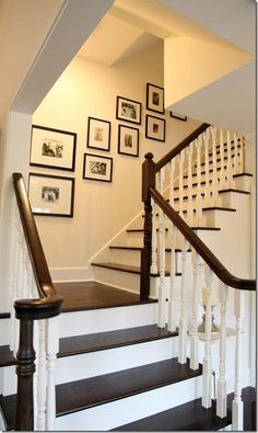 a staircase with framed pictures on the wall and wooden handrails, along with black and white stairs