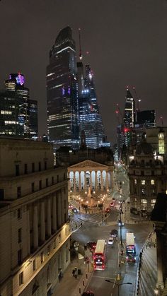 the city skyline is lit up at night, with skyscrapers in the background and cars parked on the street