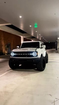 a white truck is parked in an empty parking garage with lights on the side of it