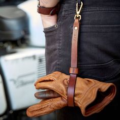 a person wearing leather gloves with one hand on the back of their glove and another holding it in his pocket