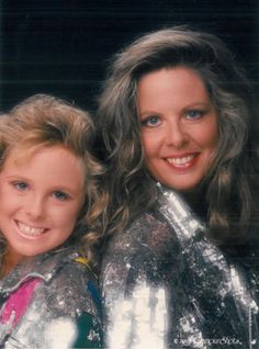 two women are posing for the camera in silver jackets and shiny clothes with their arms around each other