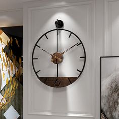 a large clock mounted to the side of a white wall next to pictures and paintings