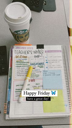 a cup of coffee sitting on top of a desk next to a notebook