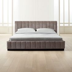 a bed that is sitting in the middle of a room with white walls and wooden floors