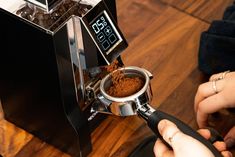 a person is using a coffee grinder to make something brown and powdered into it