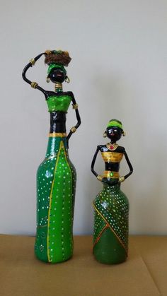 two green vases sitting next to each other on top of a wooden table with a white wall in the background