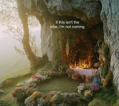 an outdoor fireplace with flowers and candles in the middle, surrounded by mossy rocks