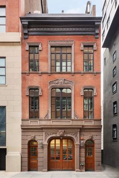 an old brick building in the middle of a city with lots of windows and doors