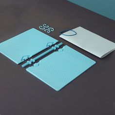 a blue notebook and some white papers on a black table with a notepad next to it