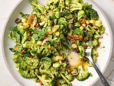 a white bowl filled with broccoli and other food on top of a table