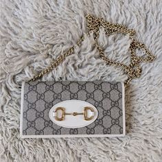 Like New, Gift-Able Condition. Comes With Original Box, Ribbon, Dust Bag, And Certificate Of Authenticity. The Chain Wallet Is Presented As Part Of The Gucci Horsebit 1955 Accessories Collection In The House's Monogram Canvas, Defined By The Double Ring And Bar Design Also Found In Handbags. The Folded Snap-Closure Shape Features Several Card Slots And Pockets, Completed With A Detachable Chain Strap. The Style Is Completed With White Leather Details. Beige/Ebony Gg Supreme Canvas White Leather Wallet With Chain, Box Ribbon, Gucci Horsebit, Chain Wallet, Double Ring, Accessories Collection, Wallet Chain, Bar Design, Monogram Canvas