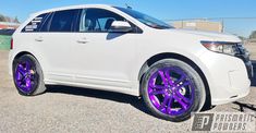 a white car with purple rims parked in a parking lot