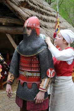 two people dressed in medieval costumes standing next to each other and one is touching the back of another person's head