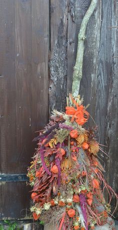 an arrangement of flowers is placed in front of a wooden fence with moss growing on it