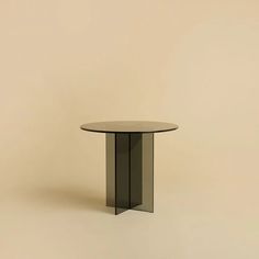 a round glass table sitting on top of a white floor next to a beige wall