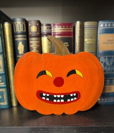 an orange pumpkin sitting on top of a wooden shelf next to bookshelves and a book case