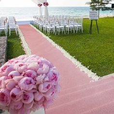 the aisle is decorated with pink flowers and white draping for an outdoor ceremony